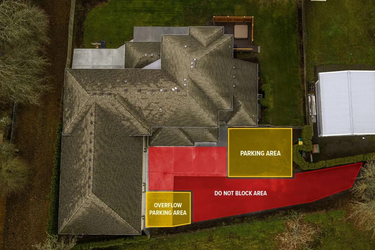 The image shows the main building structure of Highland Gables, the long private driveway leading up to it, ample marked parking areas, and lush surrounding greenery. The open field bordering the property is visible, emphasizing seclusion and spaciousness.