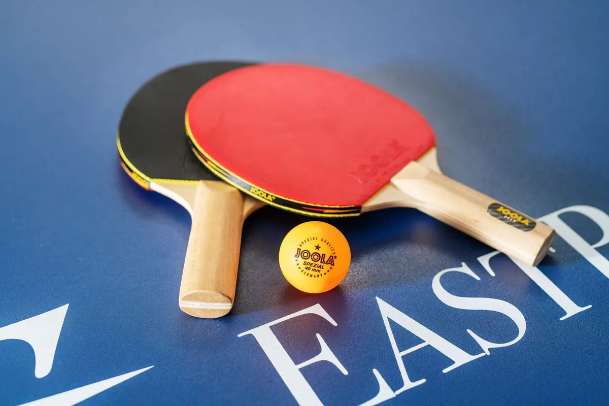 A close-up of ping pong paddles and a ball, capturing the spirit of friendly indoor competition. The image evokes the lively energy of a game room filled with opportunities for fun and connection.