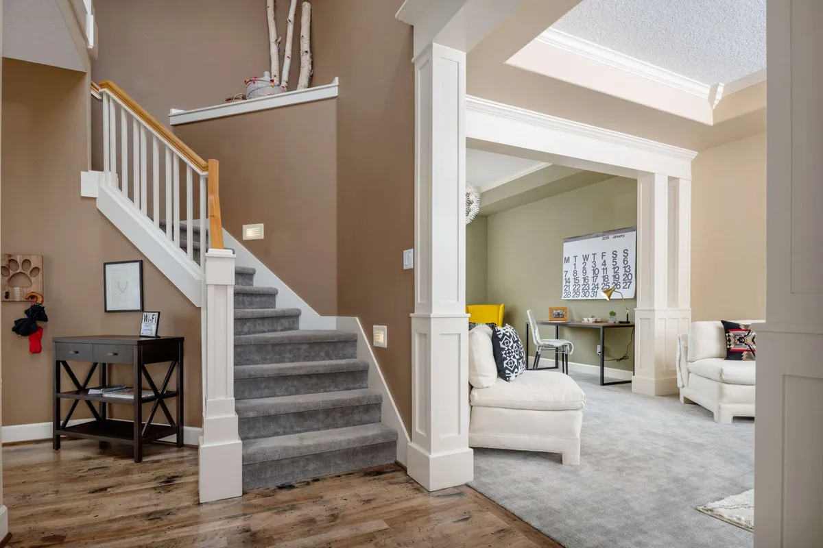 A thoughtfully designed space featuring a staircase, cozy seating area, and a desk equipped with a calendar, blending relaxation with productivity. The welcoming atmosphere makes it suitable for creative work sessions or casual conversations between colleagues.