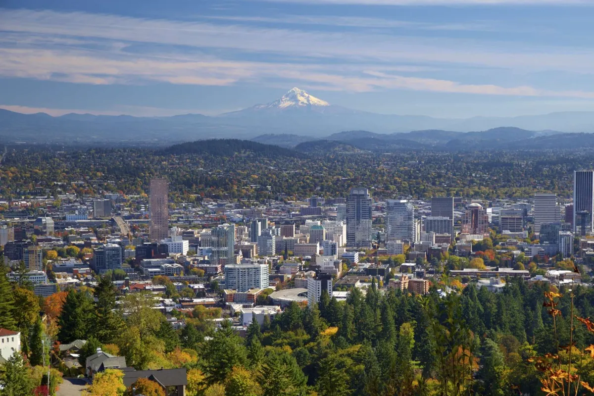 This image captures the city skyline with Mount Hood in the distance, surrounded by lush greenery and the vibrant hues of autumn. The sweeping view showcases the harmonious blend between urban life and natural beauty found in the Beaverton/Portland area.