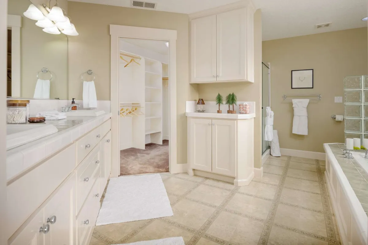 A modern bathroom with a double vanity, spacious bathtub, and walk-in closet. The atmosphere is tranquil and organized, ideal for both morning routines and evening relaxation.